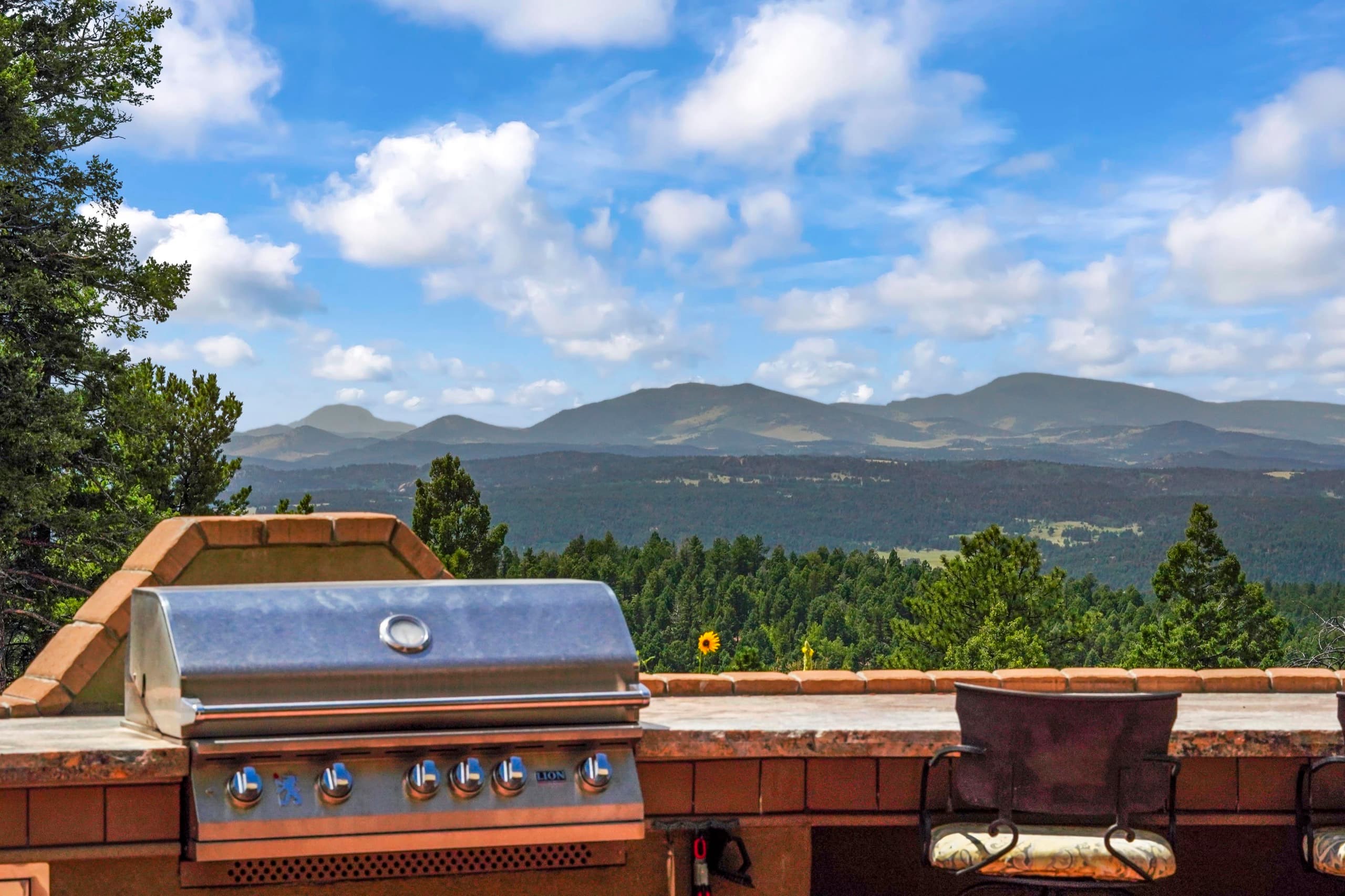 The outdoor kitchen on the patio, looking out over forested ridges toward the Pikes Peak massif